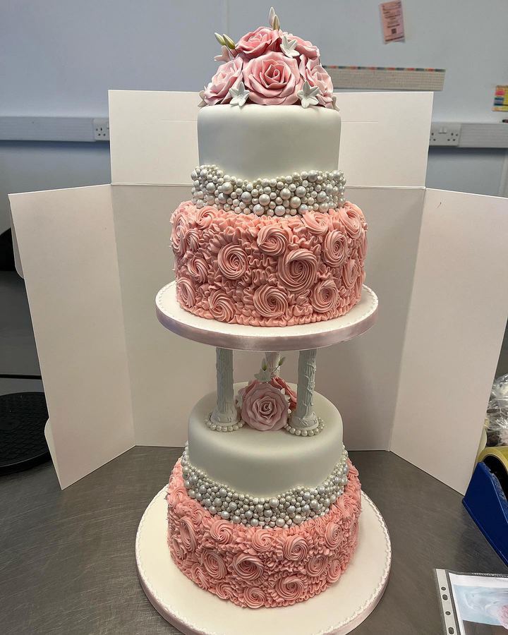 Three-tier pink and white wedding cake with sugar roses and pearls