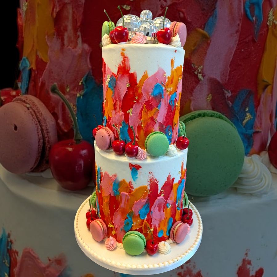 Two-tier painted cake with macarons and cherries